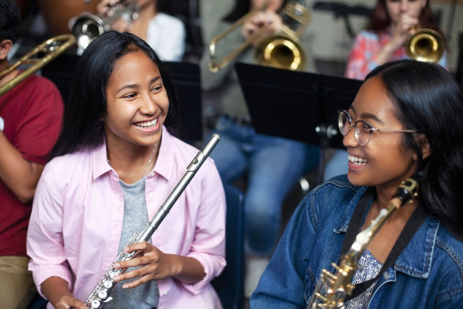 a student flute player and a student saxophone player smile as they attend band 